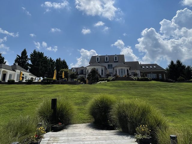 Little Ferry Inn seen from the dock: a wide lawn rising to the inn under a blue sky